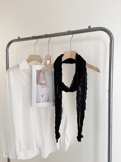 Black crinkled scarf looped over a wooden hanger
