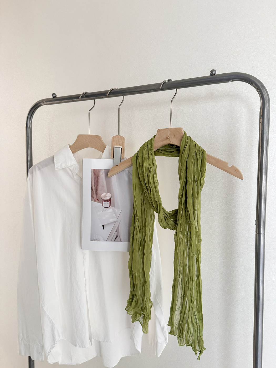 Green crinkled scarf looped over a wooden hanger
