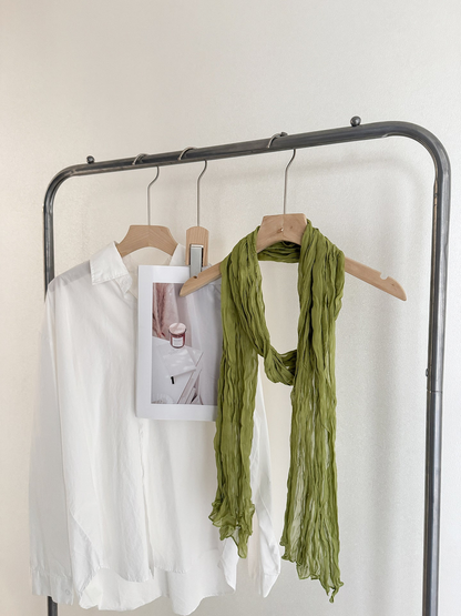 Green crinkled scarf looped over a wooden hanger