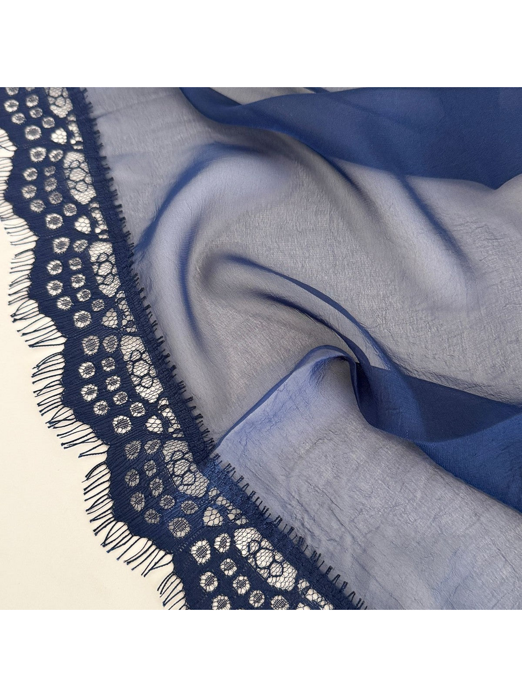 Close-up of circular lace openwork, eyelash fringe and sheer scarf fabric