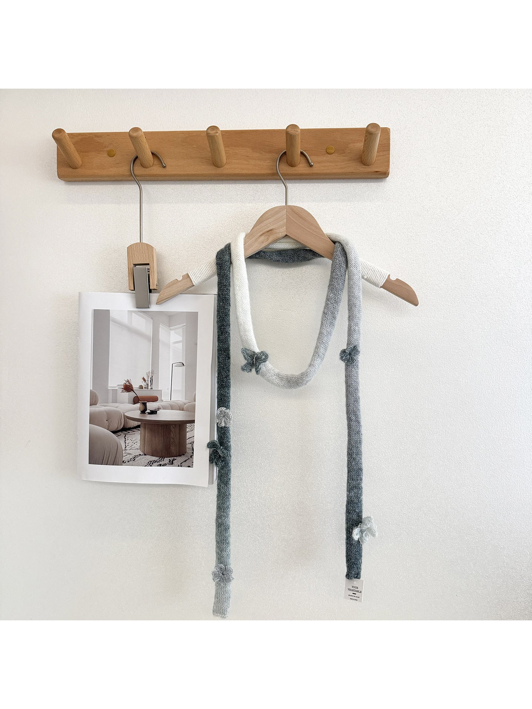 Gray knit scarf looped over a wooden hanger with raised flower and butterfly embellishments