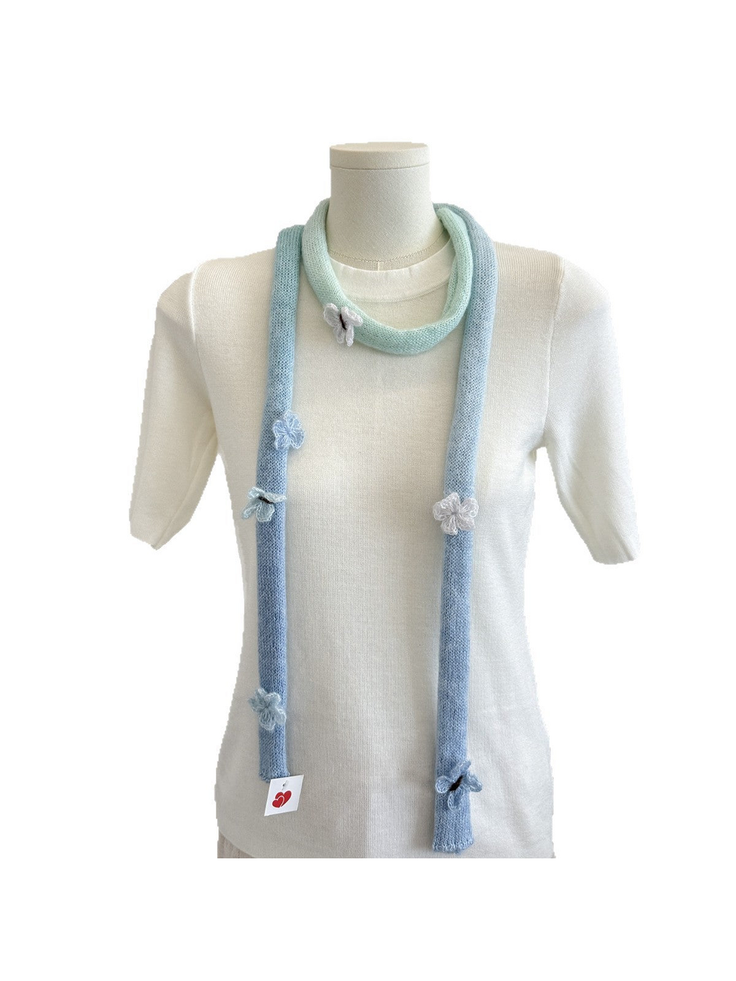 Blue knit scarf with mint gradient and raised embellishments draped on a mannequin