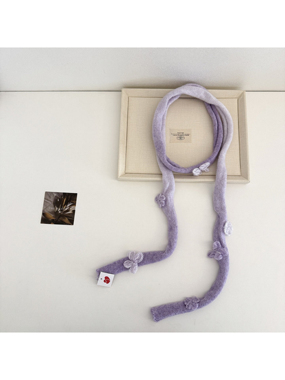 Purple knit scarf laid in a loop with pale gradient sections and raised embellishments