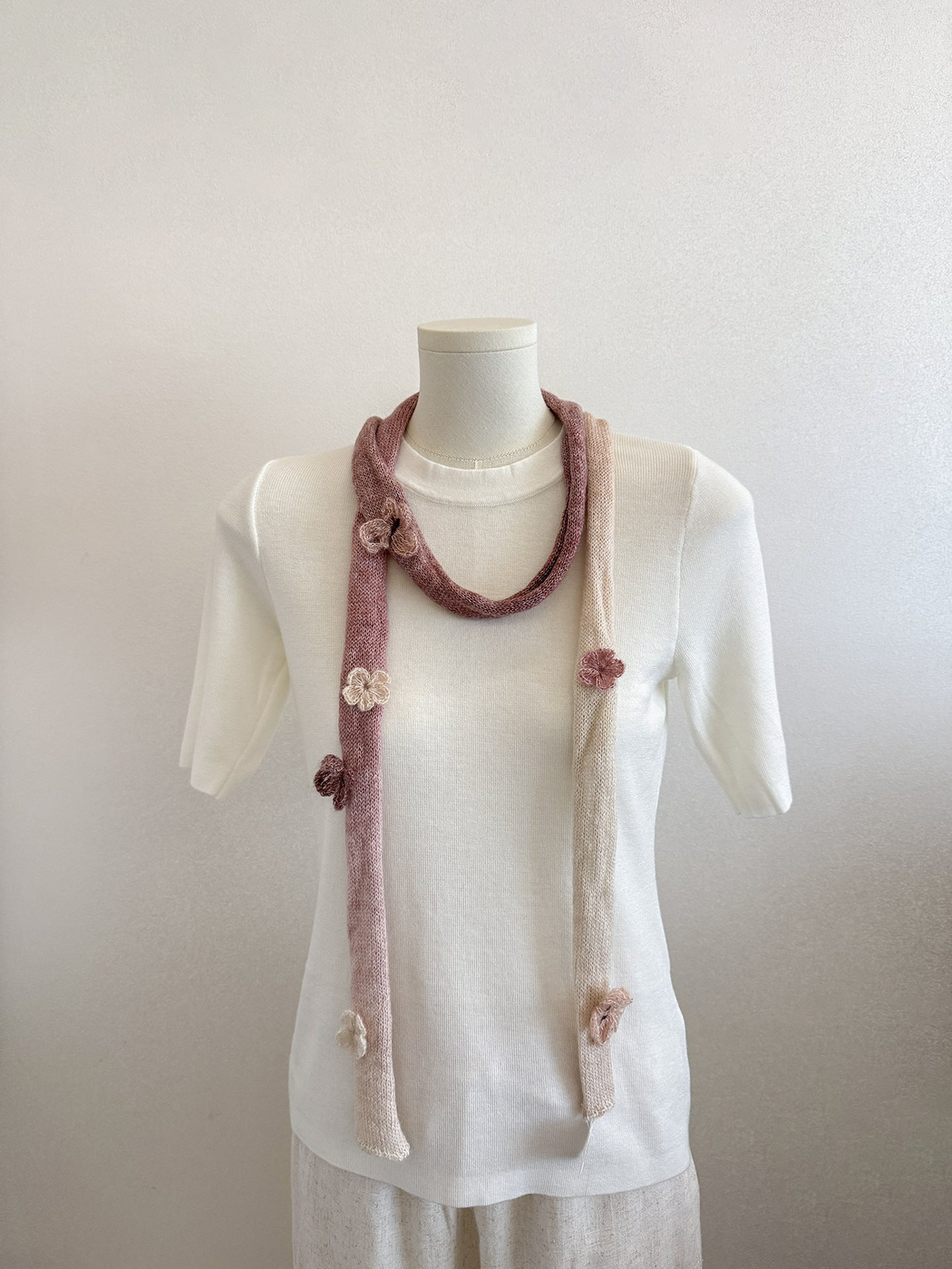 Brown gradient knit scarf with raised flower and butterfly embellishments draped on a mannequin