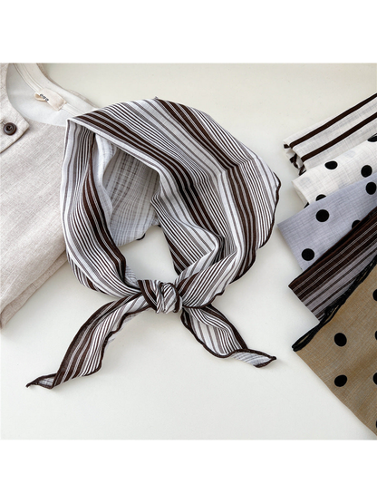 Grouped striped scarf tied beside folded polka dot and striped scarves