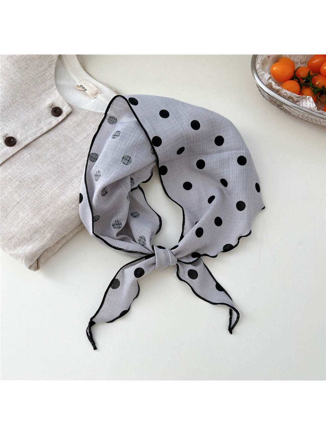 Light Gray Dots triangle scarf tied in a loop with black stitched edges