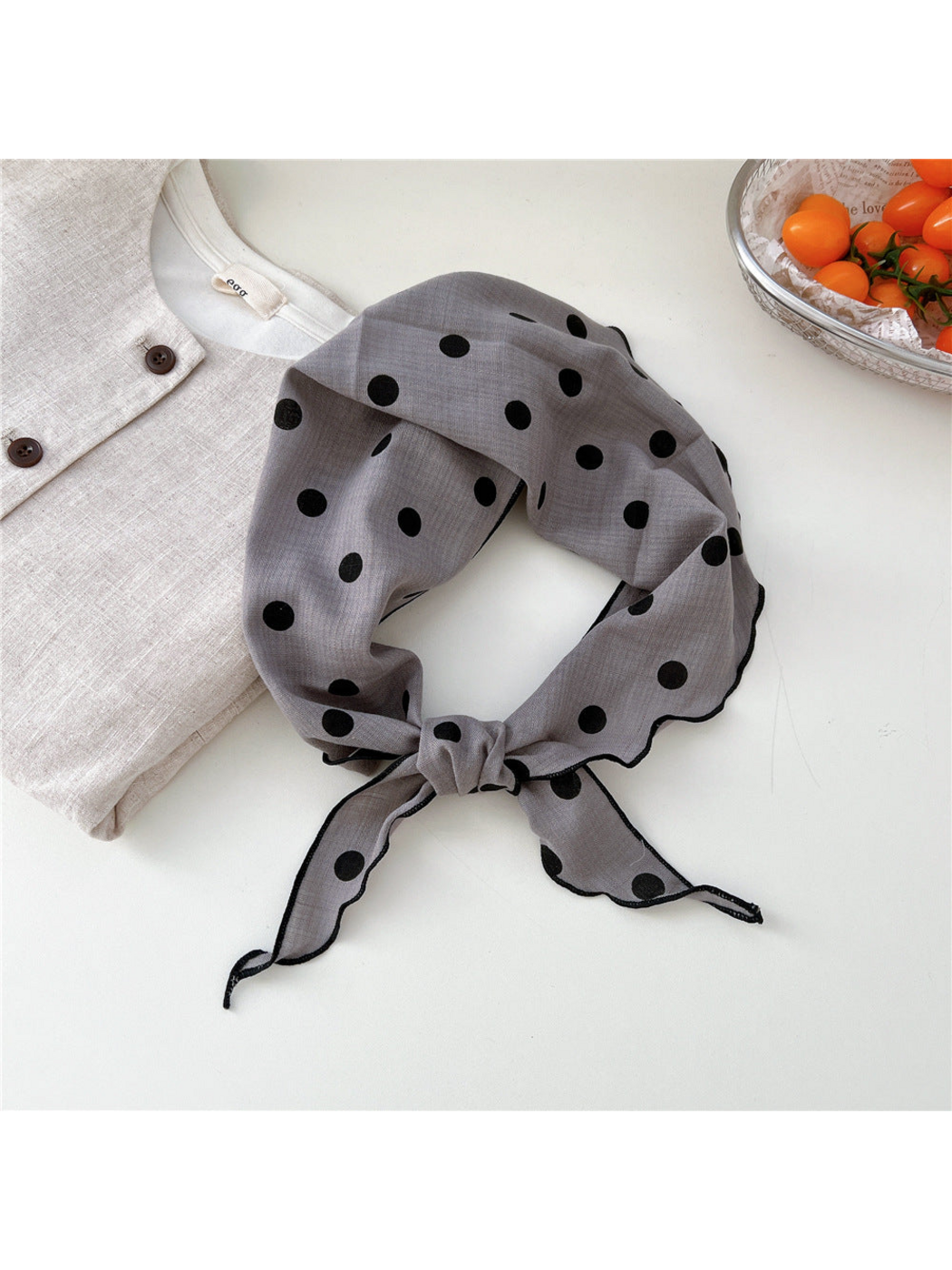 Gray Dots triangle scarf tied in a loop with black stitched edges