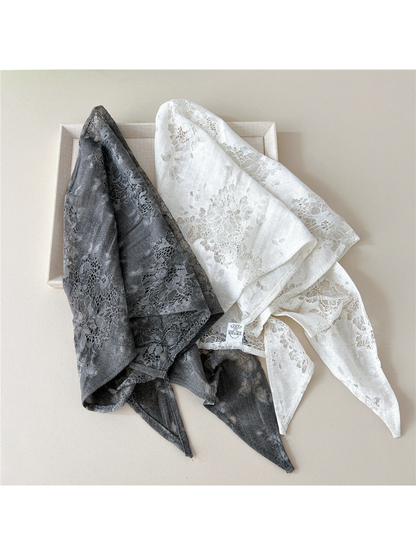 Gray and White floral lace scarves loosely folded together with an attached cloth label