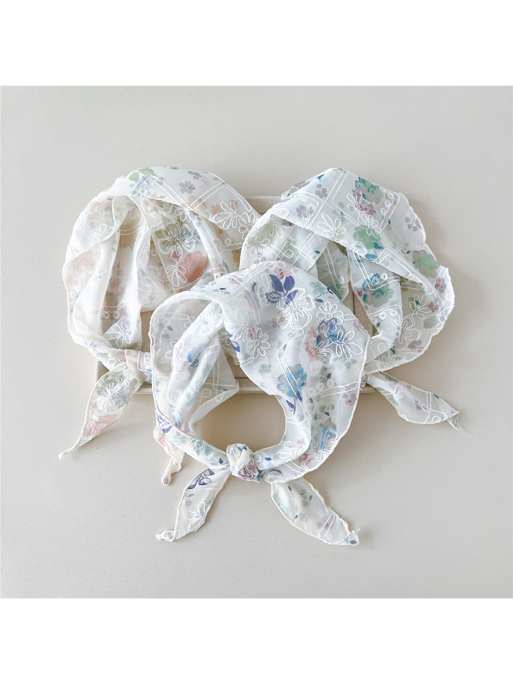 Three floral scarves with white embroidery arranged in tied loops