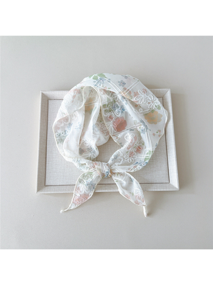 Pink floral scarf with white embroidery tied in a loop on a tray