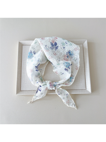 Purple floral scarf with white embroidery tied in a loop on a tray