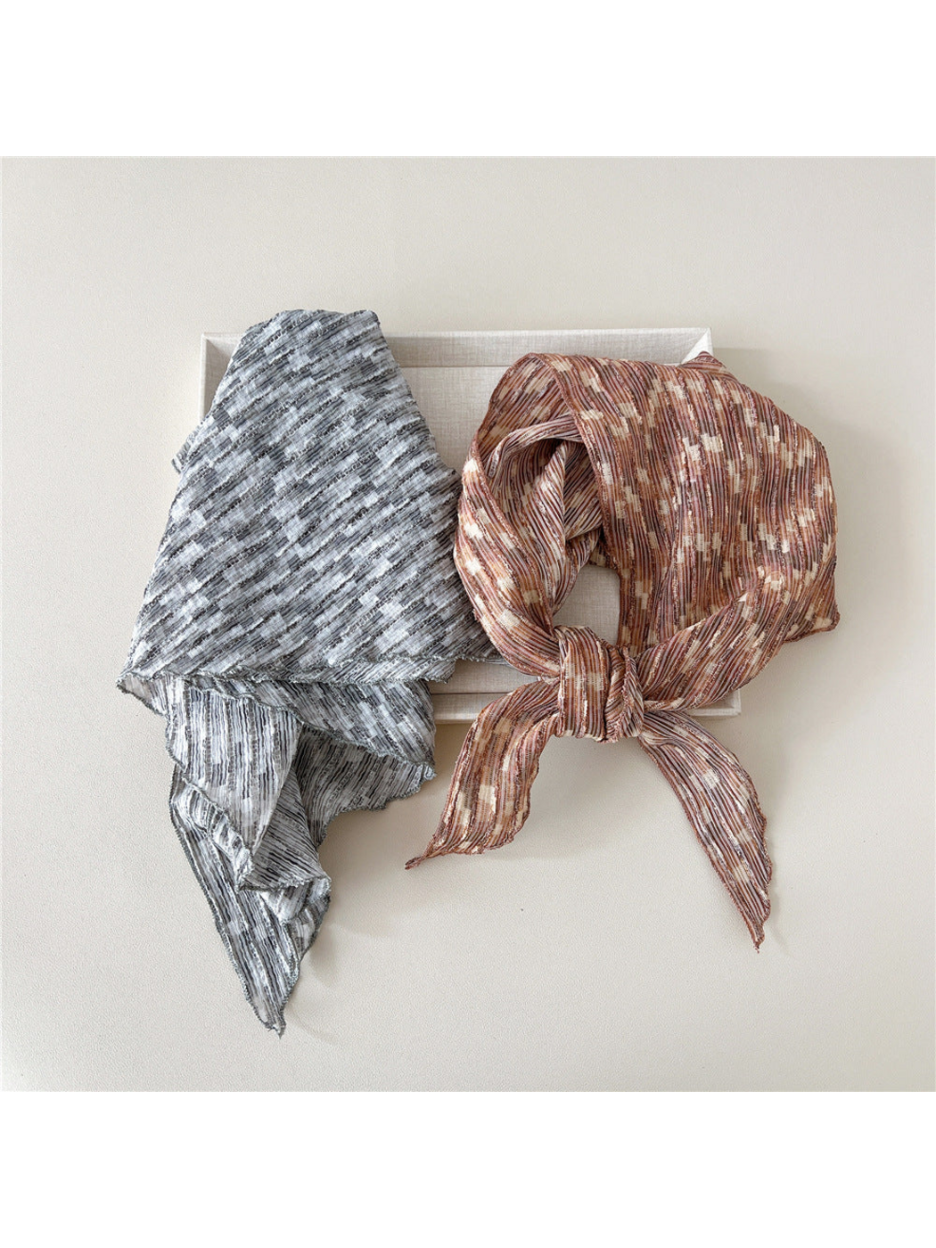 Gray striped scarf folded beside a knotted Brown triangle scarf