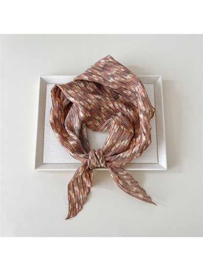 Brown striped triangle scarf arranged in a broad loop with a knot and two pointed ends