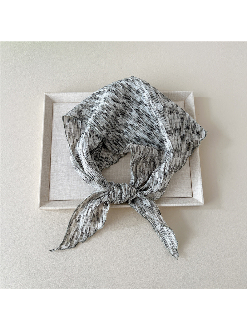 Gray striped triangle scarf looped with a front knot and two pointed ends