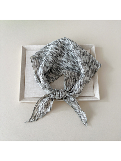 Gray striped triangle scarf looped with a front knot and two pointed ends