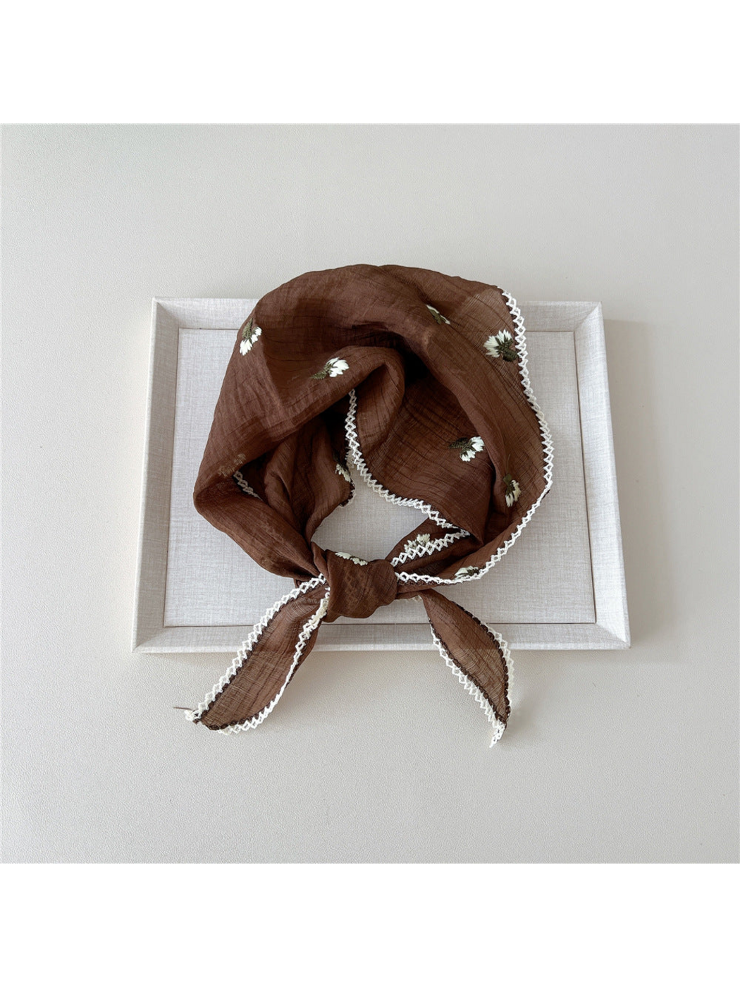 Brown floral scarf in a knotted loop with white openwork edge trim