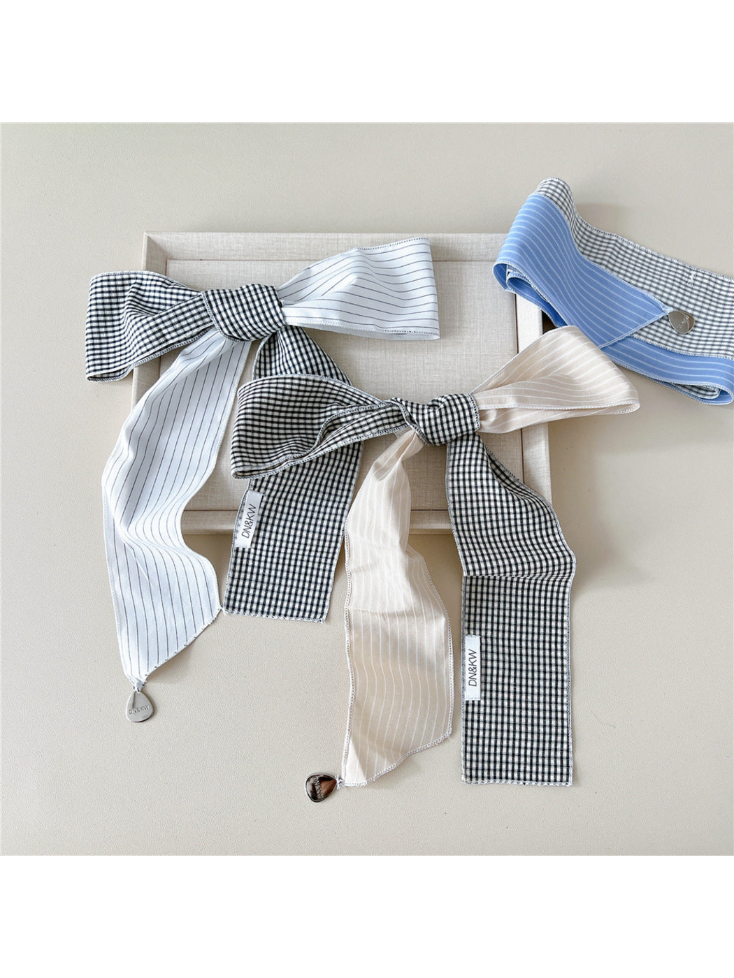 White and Beige scarves tied in bows beside a folded Blue scarf
