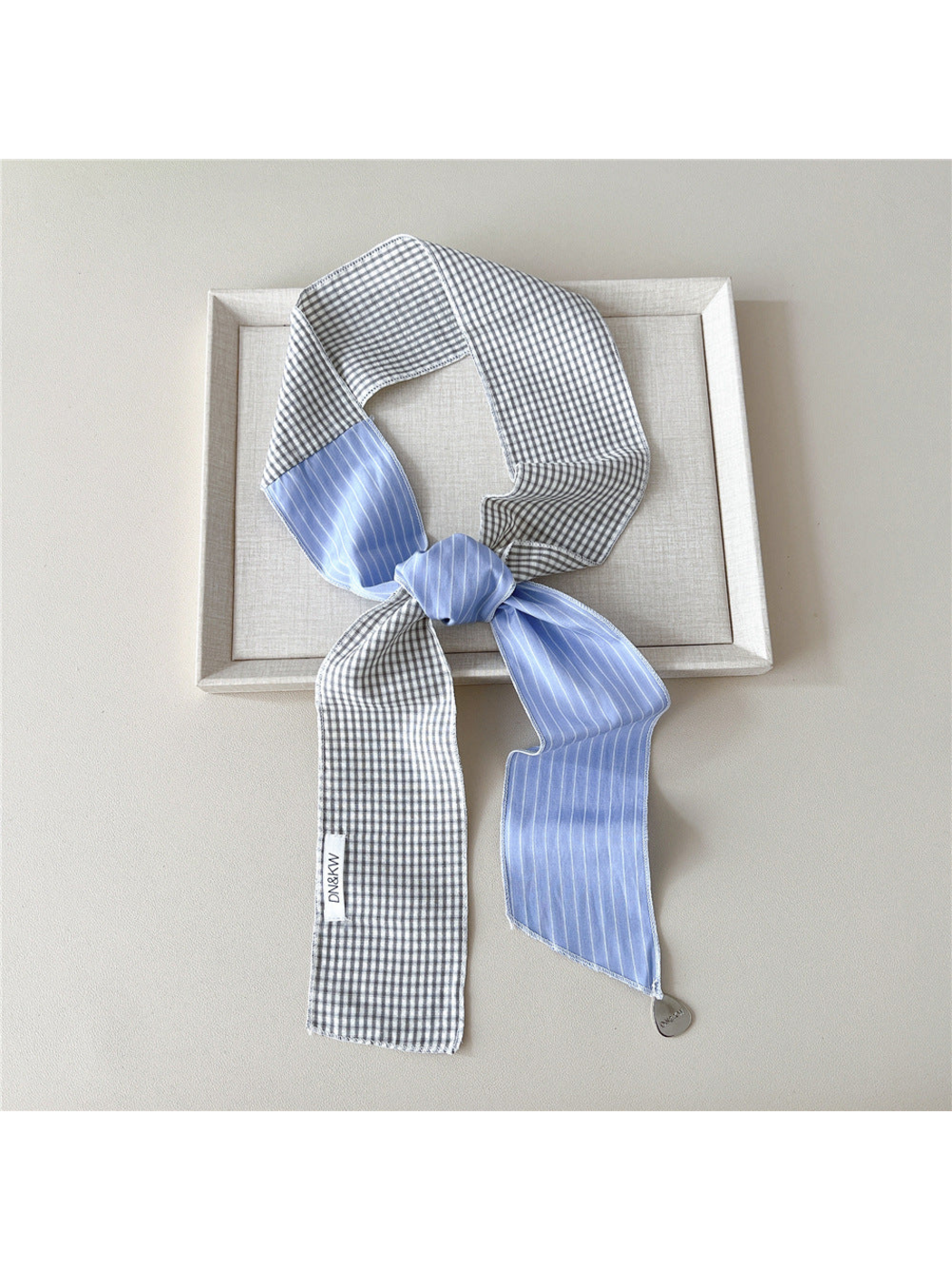 Blue scarf with gray gingham checks and white stripes tied in a knotted loop