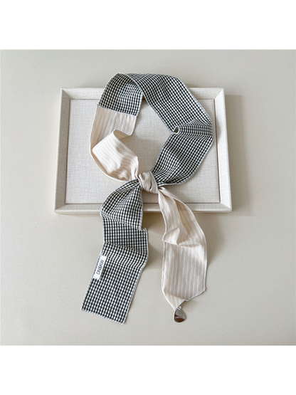Beige scarf with black and white gingham checks tied in a knotted loop