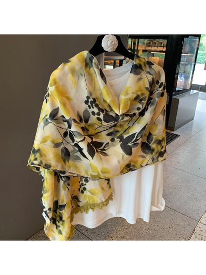 Multicolor botanical-print scarf draped broadly across the shoulders, with one trimmed end hanging down