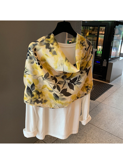 Multicolor botanical-print scarf arranged in a short cowl drape over a white top