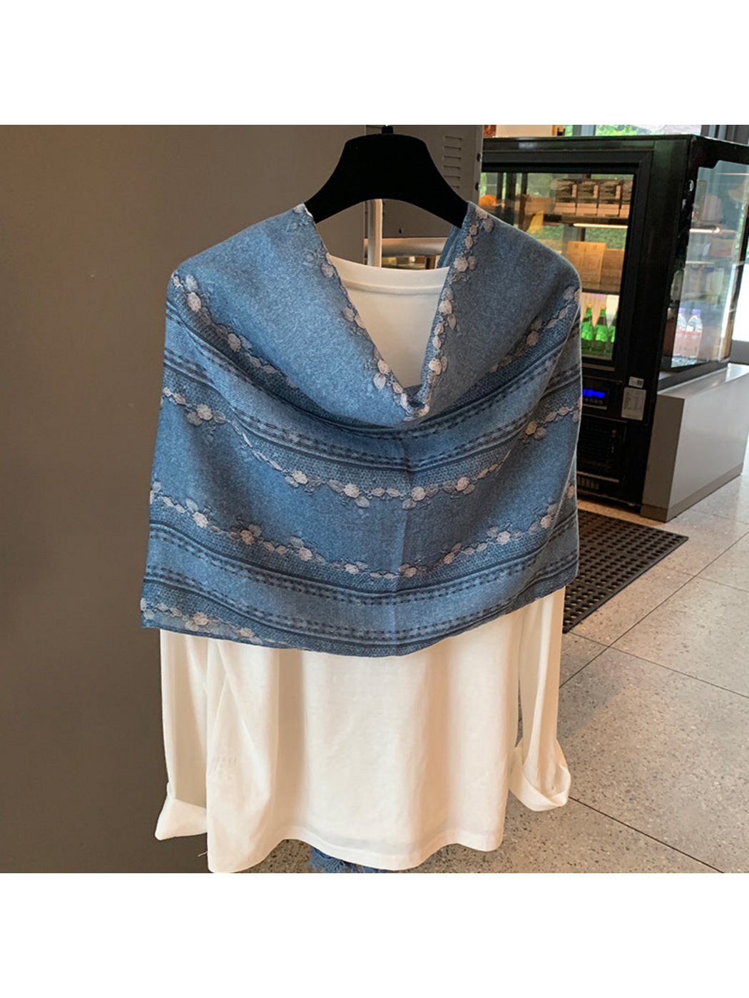Blue floral and striped scarf draped as a short shoulder wrap