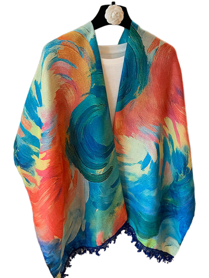 Blue scarf with multicolored painterly swirls and dark blue fringe, hanging in an open drape
