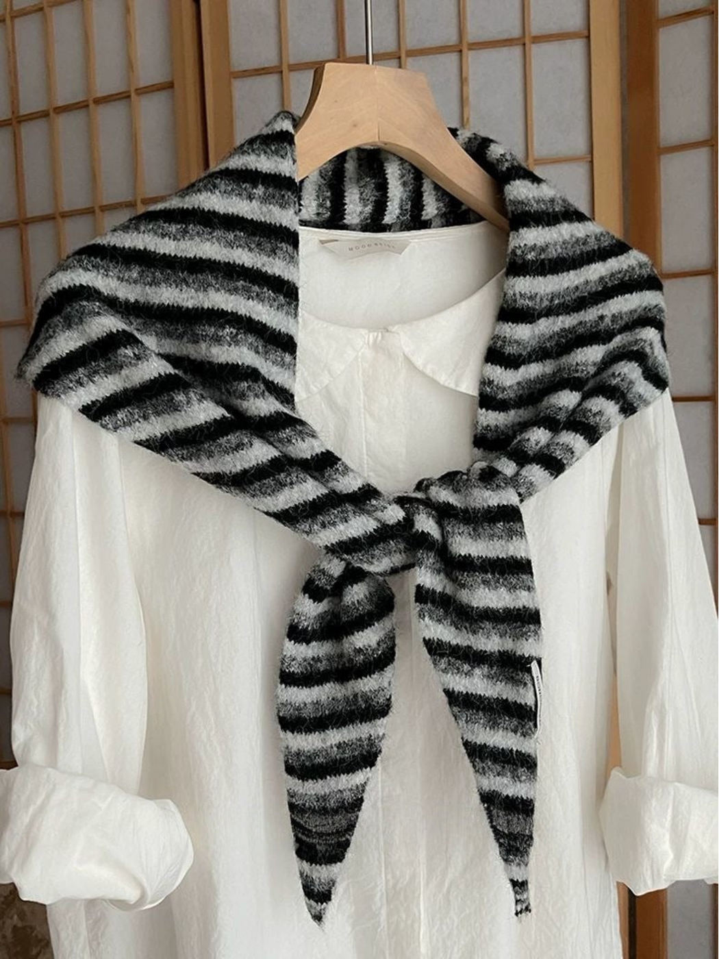Black striped scarf tied over a white shirt