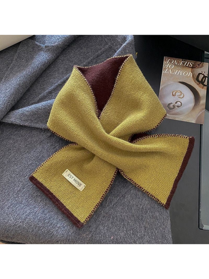 Mustard knit scarf with contrasting trim, looped on gray fabric