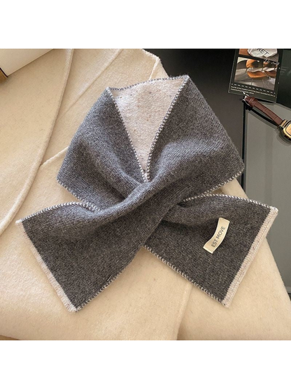 Gray knit scarf with contrasting white trim, looped on cream fabric
