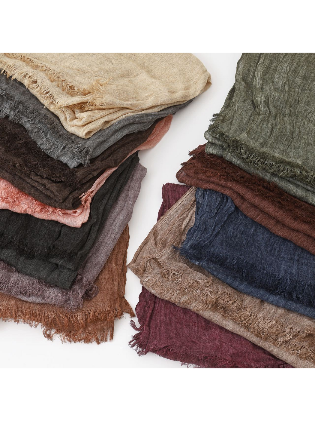 Stacked scarves in assorted solid colors showing crinkled texture and fringed edges