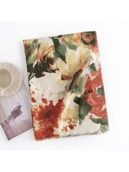 Beige floral scarf folded on a white surface beside a cup and magazine