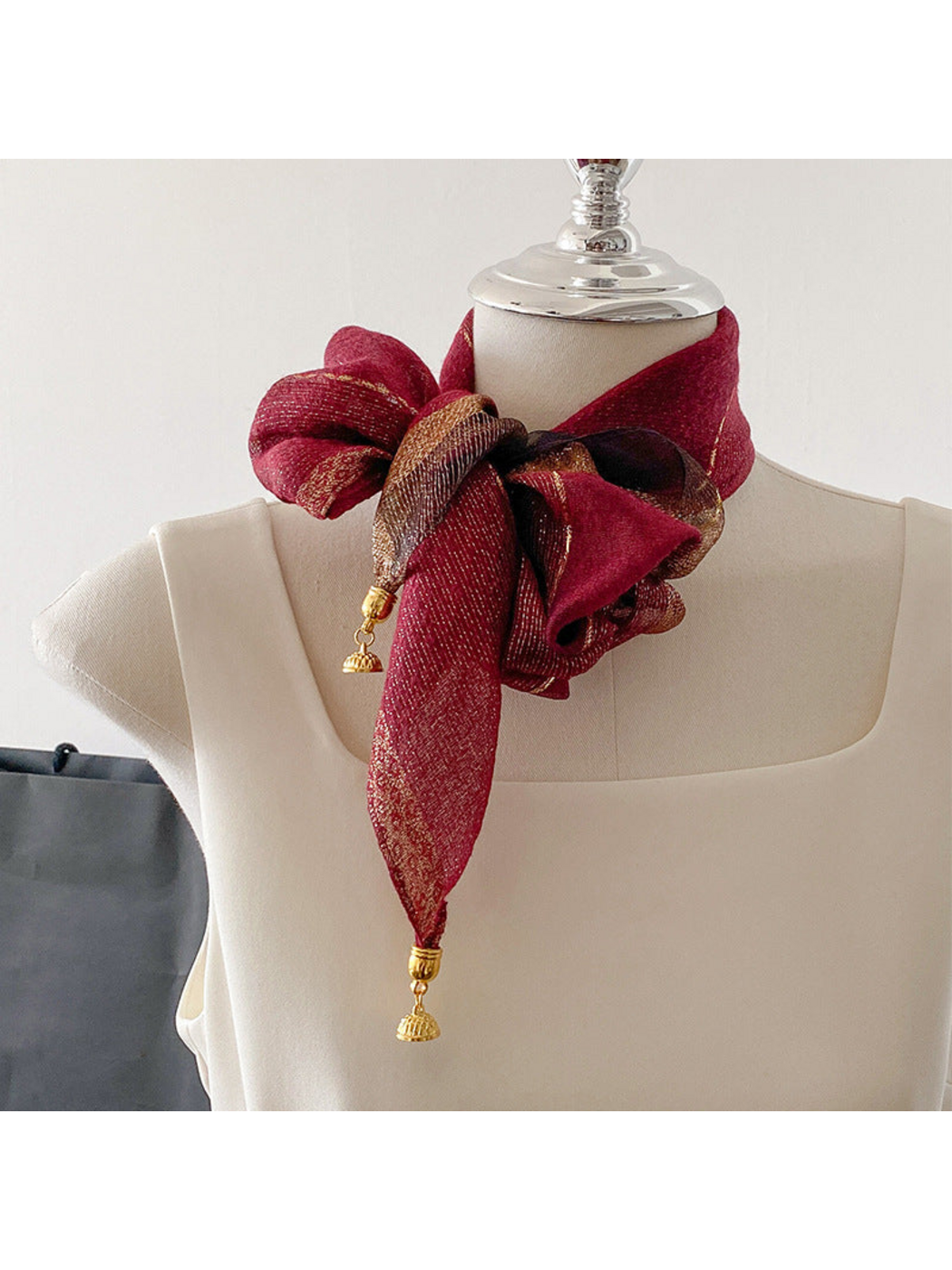 Burgundy scarf tied in a looped bow with gold-tone end ornaments