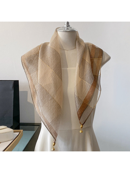 Beige scarf draped on a mannequin with metallic-look lines and gold-tone end ornaments