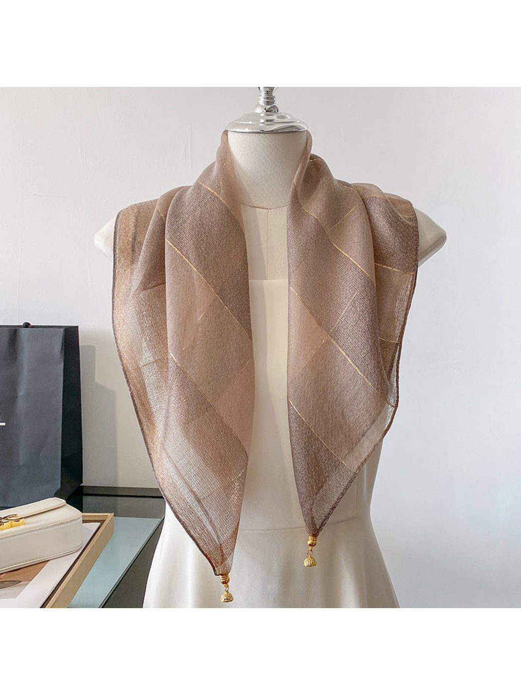 Coffee scarf draped on a mannequin with metallic-look lines and gold-tone end ornaments