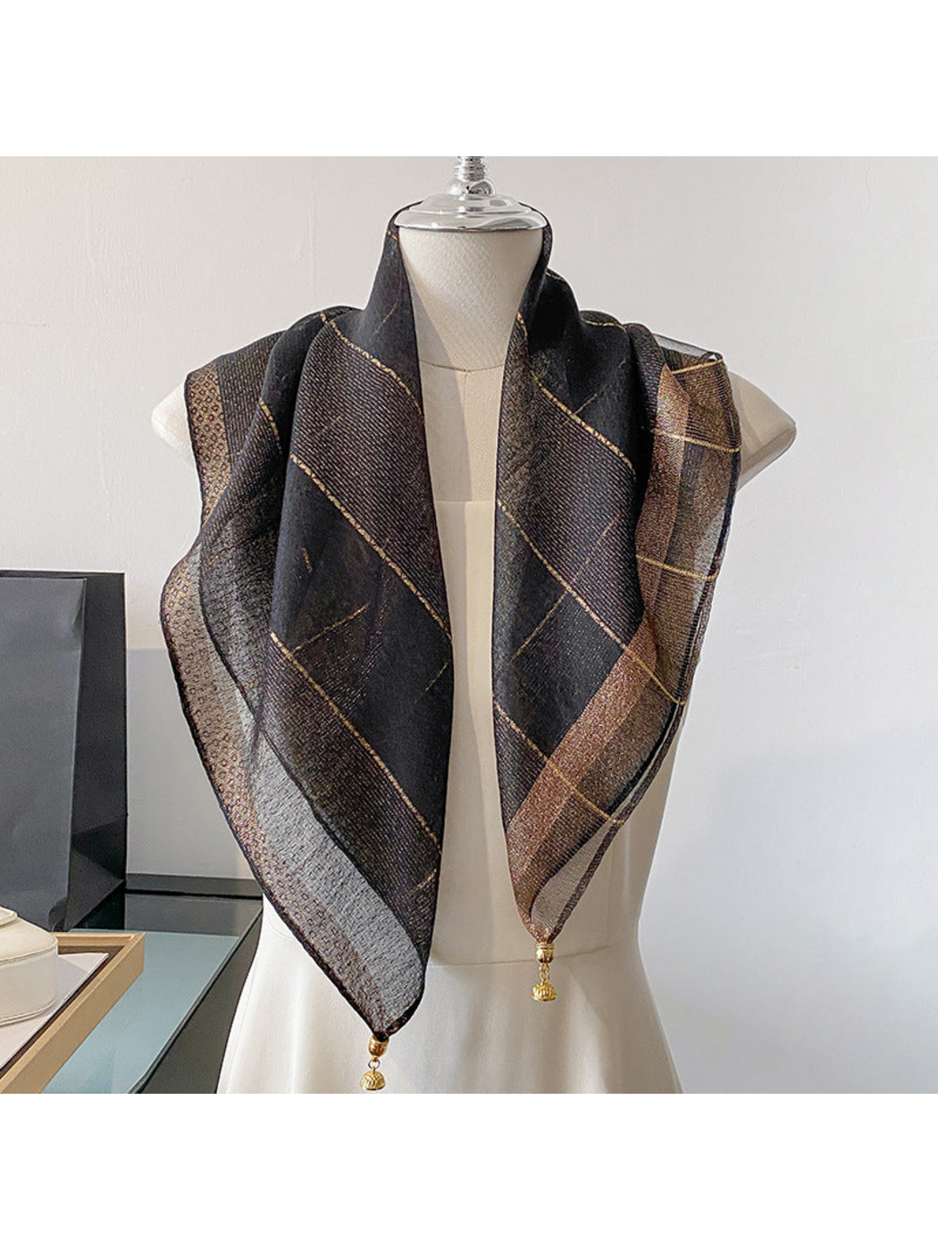 Black scarf draped on a mannequin with metallic-look lines and a contrasting border