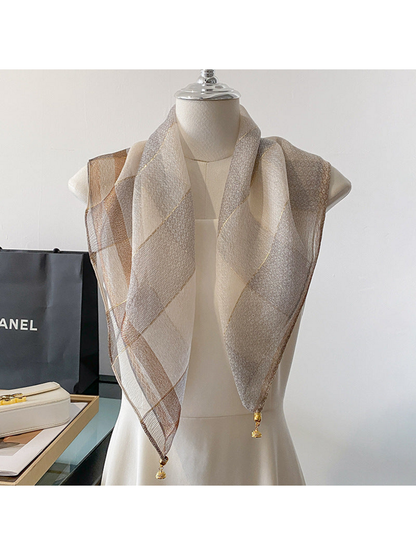 Silver scarf draped on a mannequin with metallic-look lines and gold-tone end ornaments
