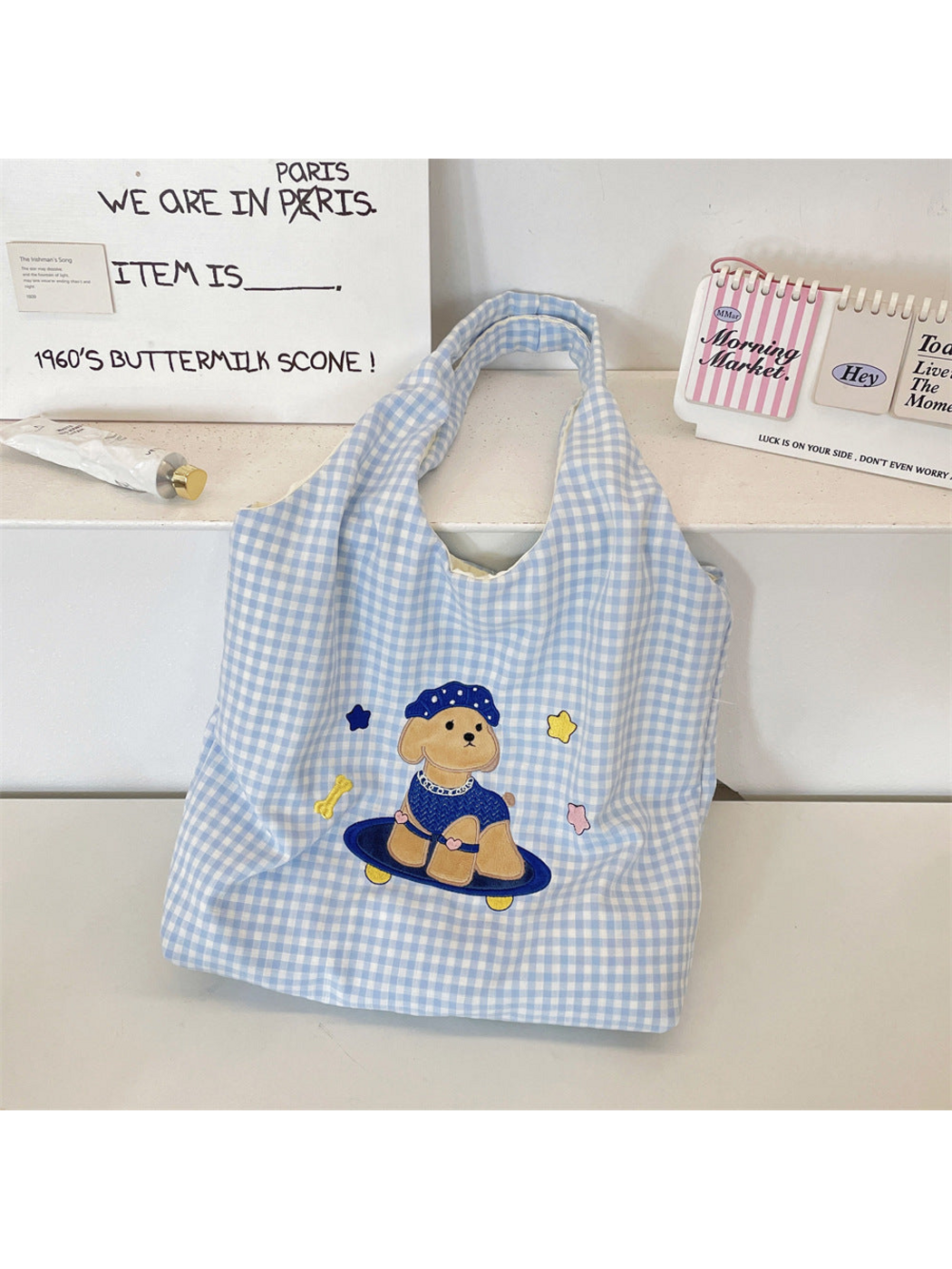 Blue gingham tote bag with a cartoon dog on a skateboard, upright front view