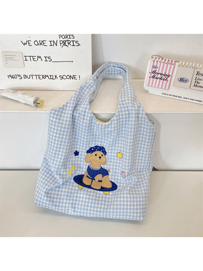 Blue gingham tote bag with a cartoon dog on a skateboard, upright front view