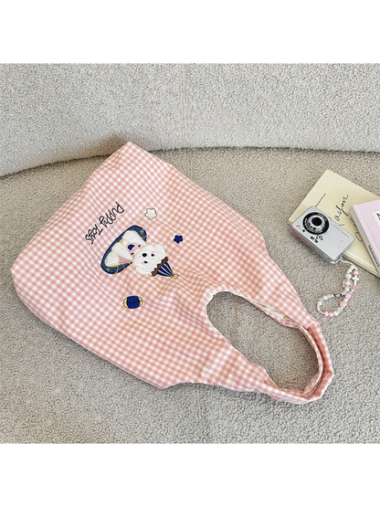 Pink gingham tote bag with a party-hat cartoon dog and Puppy Toys lettering, diagonal flat view
