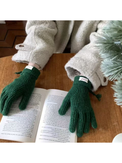 Green ribbed gloves worn over an open book