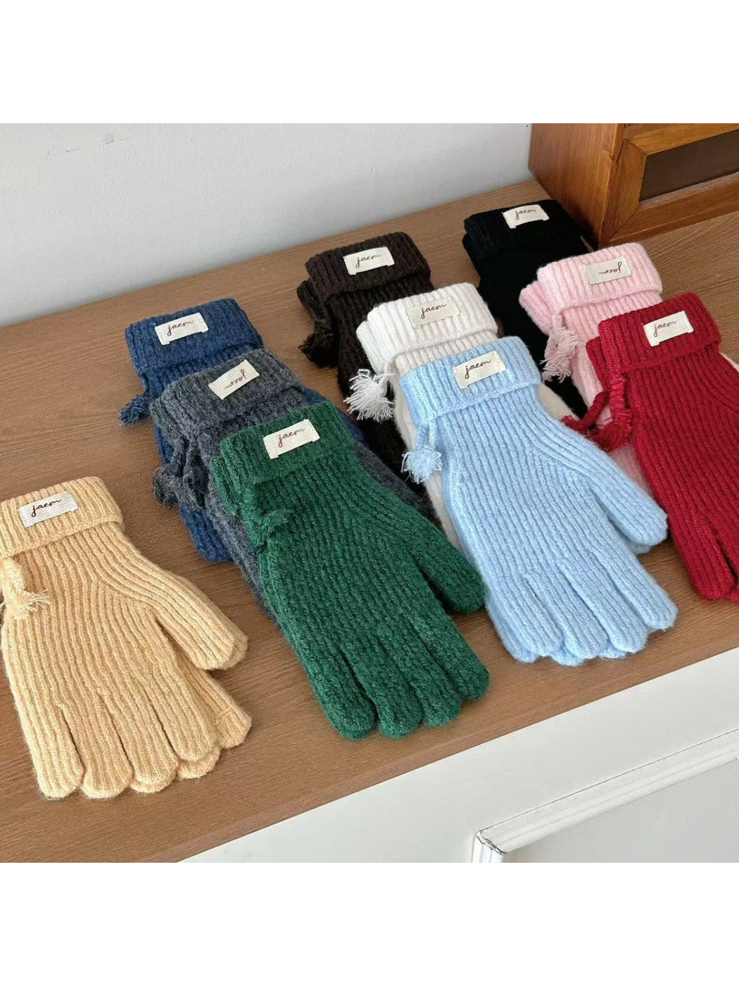 Ribbed gloves in assorted colors arranged on a wooden surface