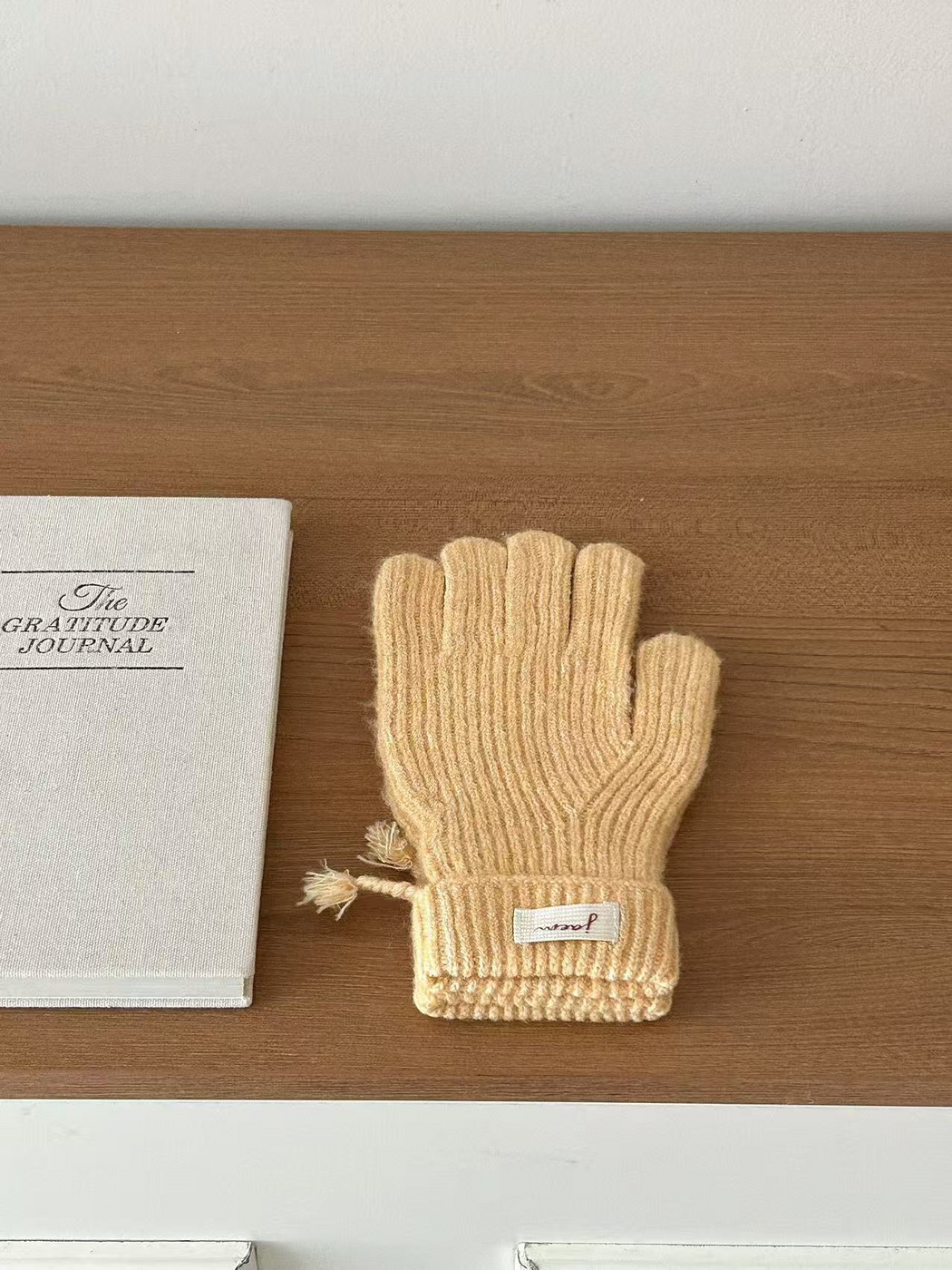 Yellow ribbed gloves with folded cuffs beside a journal