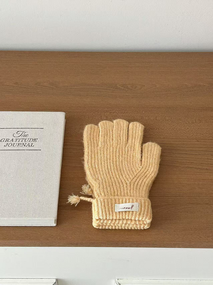 Yellow ribbed gloves with folded cuffs beside a journal