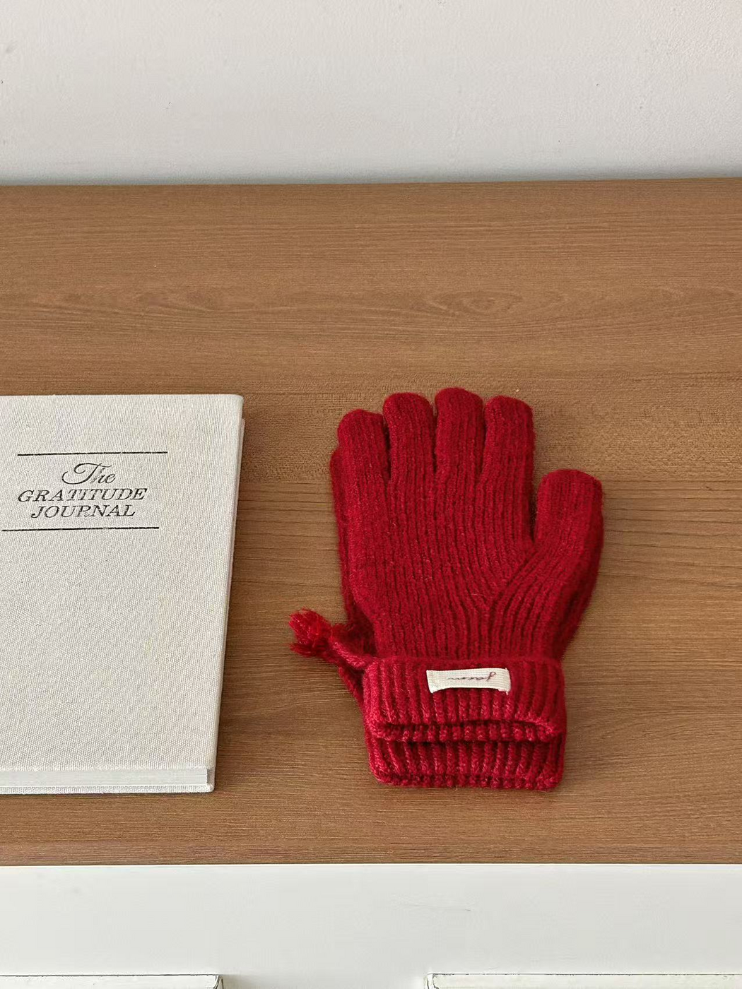 Burgundy ribbed gloves with folded cuffs beside a journal