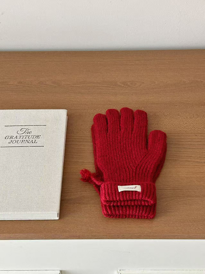 Burgundy ribbed gloves with folded cuffs beside a journal