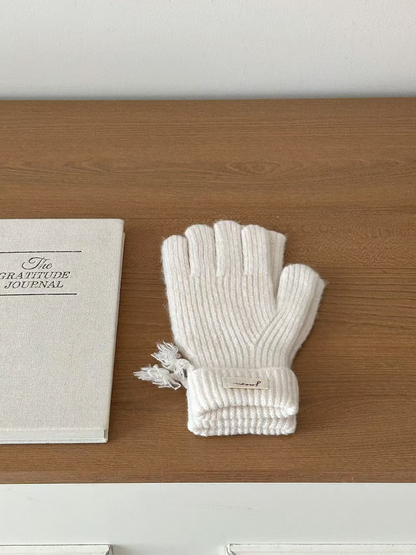 Ivory ribbed gloves with folded cuffs beside a journal
