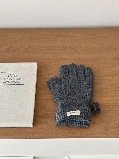Gray ribbed gloves with folded cuffs beside a journal