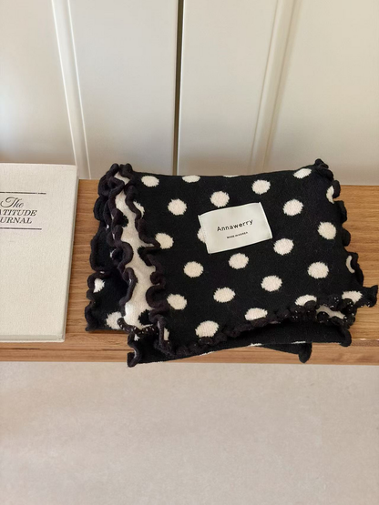 Black polka dot scarf folded with its contrasting reverse visible