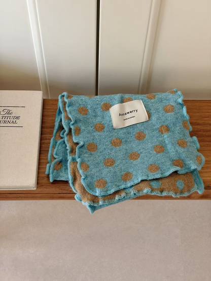 Turquoise polka dot scarf folded with its camel reverse and ruffled edges visible